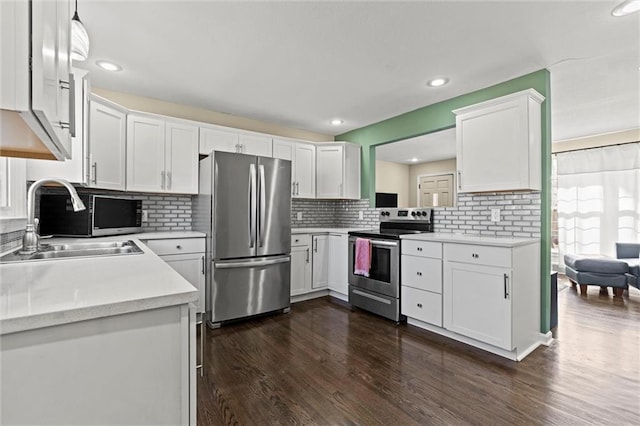 kitchen featuring dark wood finished floors, stainless steel appliances, light countertops, white cabinetry, and a sink