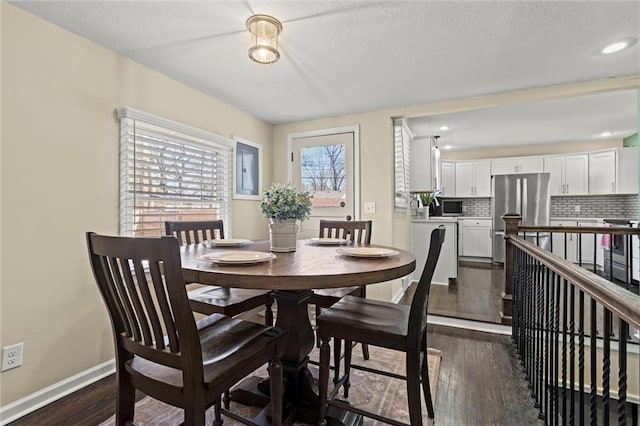 dining area featuring dark wood-style floors, baseboards, and a textured ceiling