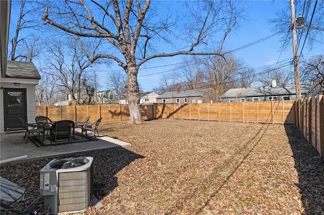 view of yard featuring a patio area, a fenced backyard, a residential view, and central AC unit