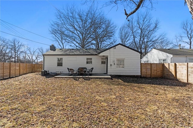 back of house featuring a patio area, a fenced backyard, a chimney, and central AC