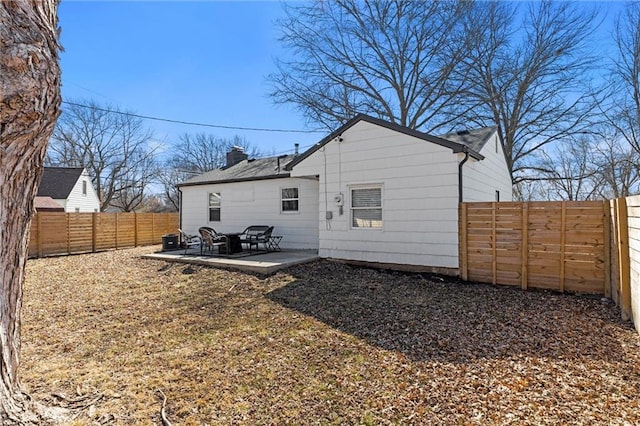 rear view of house with a fenced backyard, a patio, and a chimney