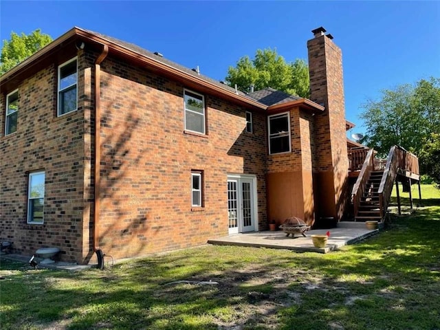 rear view of house with an outdoor fire pit, a patio area, a lawn, french doors, and a wooden deck