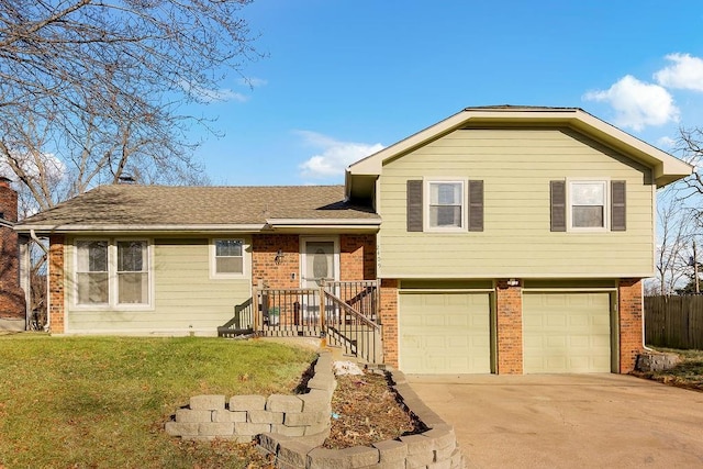 split level home featuring a garage, a front yard, brick siding, and driveway