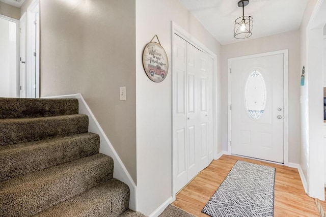 foyer entrance featuring light wood-style flooring, baseboards, and stairs