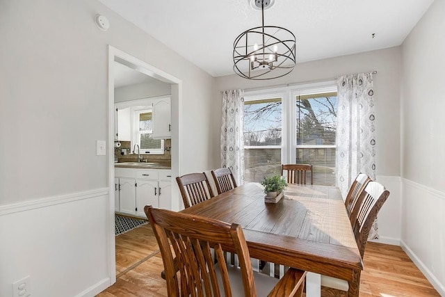 dining room featuring a chandelier, light wood finished floors, and baseboards