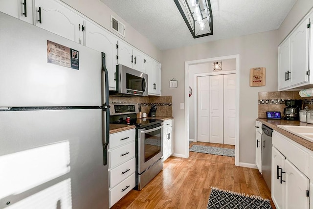 kitchen with light wood-style floors, white cabinetry, visible vents, and stainless steel appliances