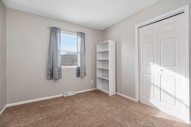 unfurnished bedroom featuring a closet, carpet flooring, visible vents, and baseboards