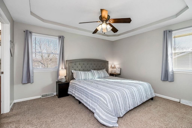 bedroom with baseboards, visible vents, and a tray ceiling