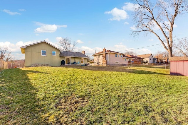 back of house featuring fence, an outdoor structure, and a yard