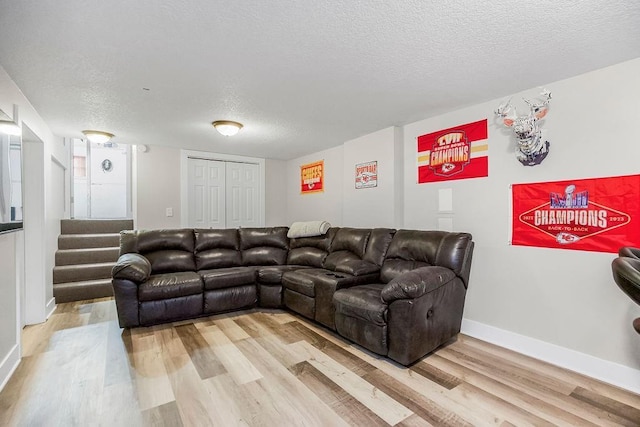 living room with light wood-style floors, stairs, baseboards, and a textured ceiling