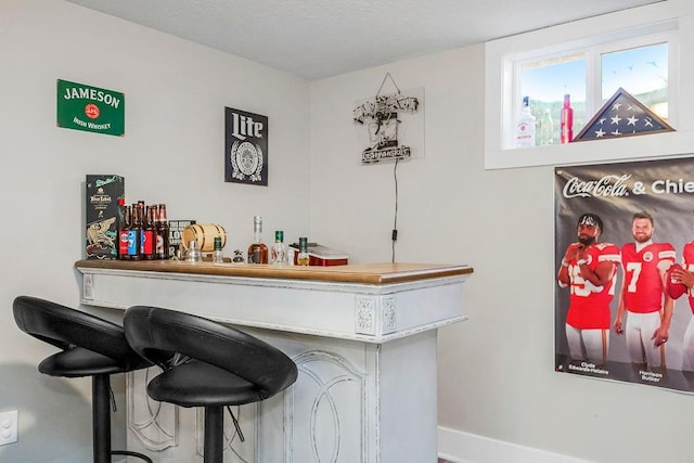 bar with a dry bar and baseboards