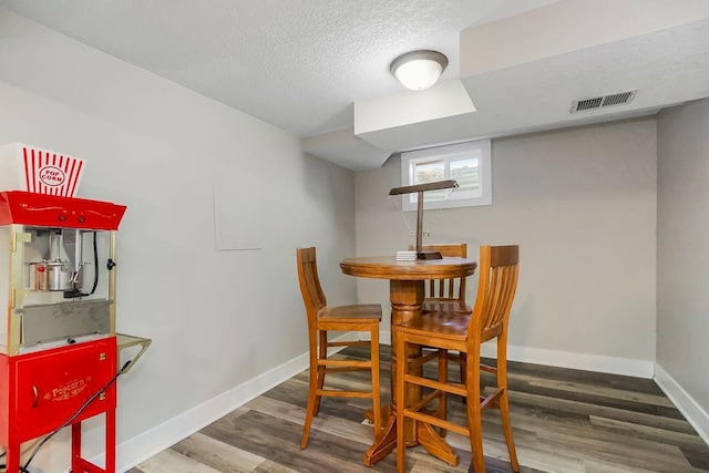 dining area featuring baseboards, a textured ceiling, visible vents, and wood finished floors