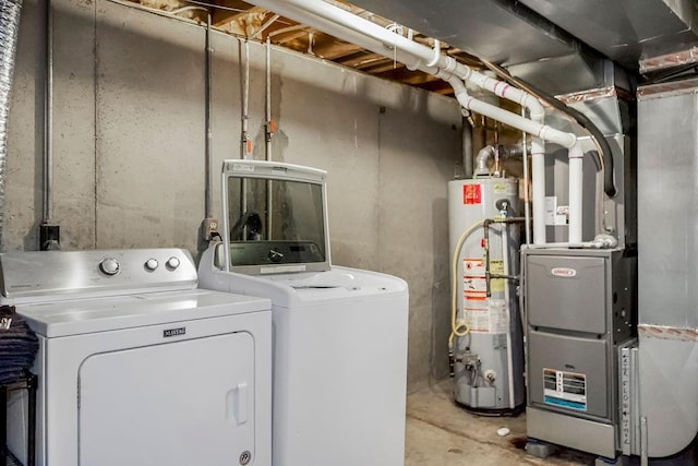 washroom with laundry area, gas water heater, washing machine and clothes dryer, and heating unit