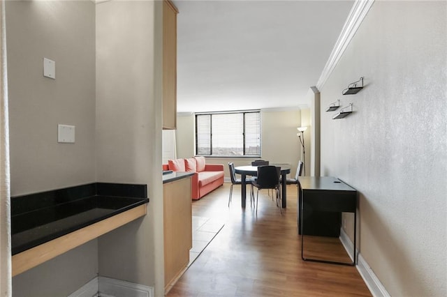 hall featuring crown molding, baseboards, and wood finished floors