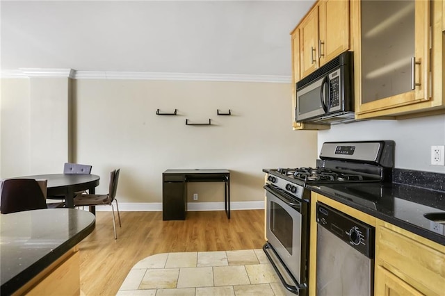 kitchen with appliances with stainless steel finishes, glass insert cabinets, ornamental molding, dark stone countertops, and baseboards