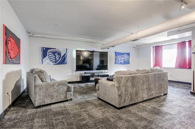 living area featuring dark colored carpet, rail lighting, and baseboards