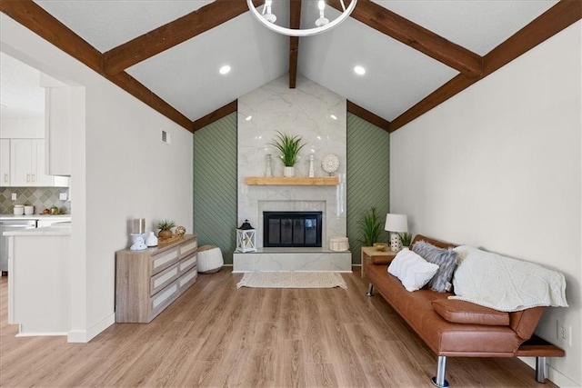 living room featuring a fireplace, visible vents, lofted ceiling with beams, light wood-style floors, and baseboards