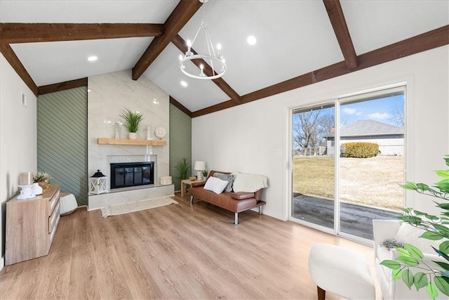 living room with a notable chandelier, vaulted ceiling with beams, light wood-style flooring, and a premium fireplace