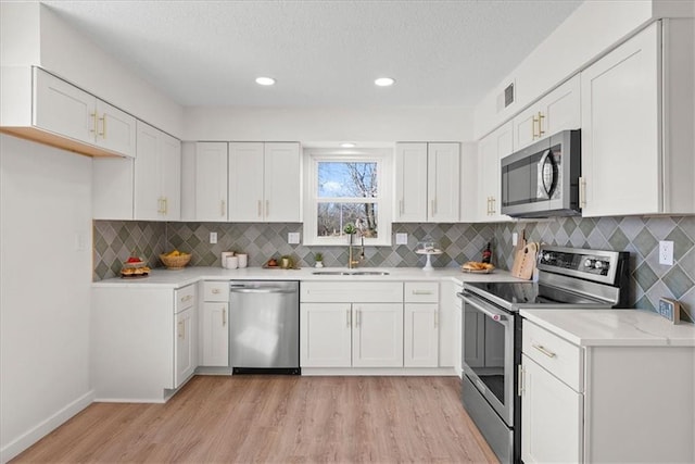 kitchen with stainless steel appliances, a sink, visible vents, and white cabinets