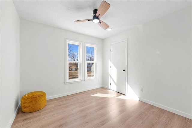 empty room featuring a ceiling fan, baseboards, and wood finished floors