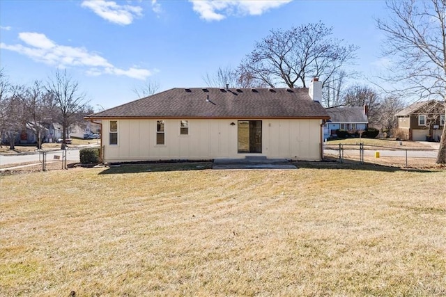 back of property featuring a shingled roof, a lawn, a chimney, and fence