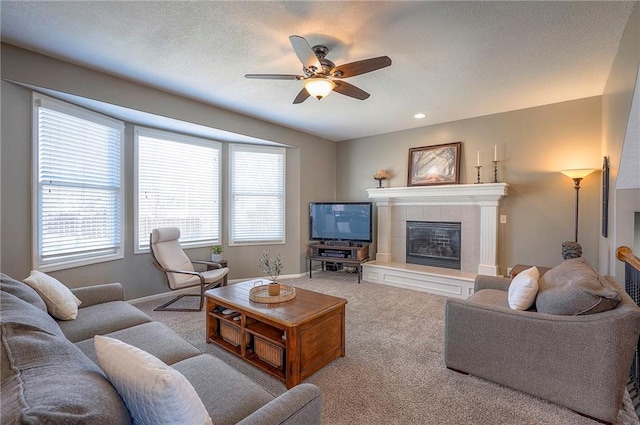 carpeted living area featuring a textured ceiling, recessed lighting, a fireplace, baseboards, and ceiling fan