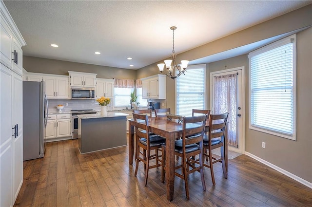 dining area with baseboards, recessed lighting, an inviting chandelier, a textured ceiling, and dark wood-style flooring