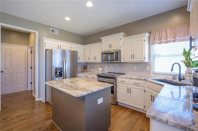 kitchen featuring a sink, a kitchen island, appliances with stainless steel finishes, and wood finished floors