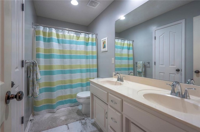 bathroom with double vanity, toilet, visible vents, and a sink