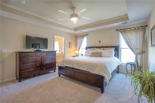 bedroom with a tray ceiling, multiple windows, visible vents, and light carpet