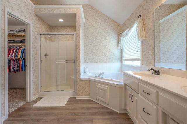 full bath featuring wallpapered walls, a shower stall, a walk in closet, and wood finished floors