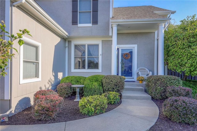 entrance to property with stucco siding and a shingled roof