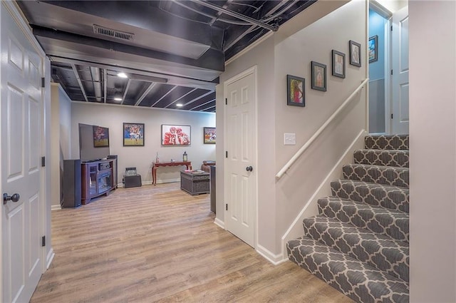 interior space featuring stairway, light wood-style flooring, baseboards, and visible vents