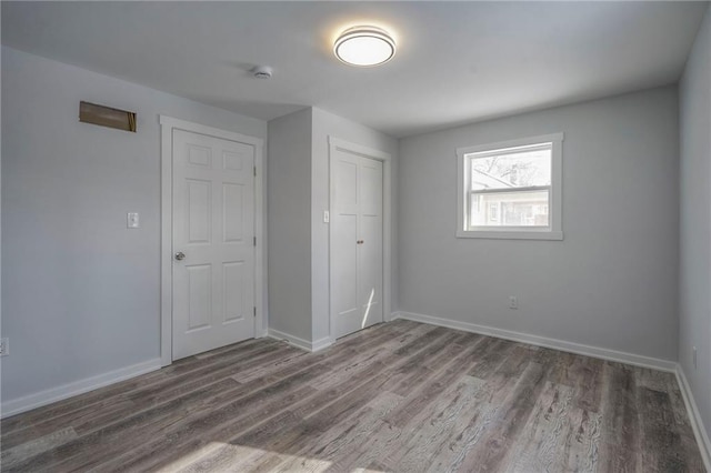 unfurnished bedroom with dark wood-style floors, a closet, and baseboards