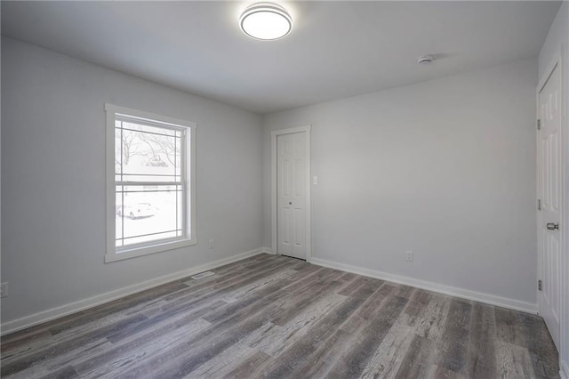 empty room featuring dark wood-style floors and baseboards