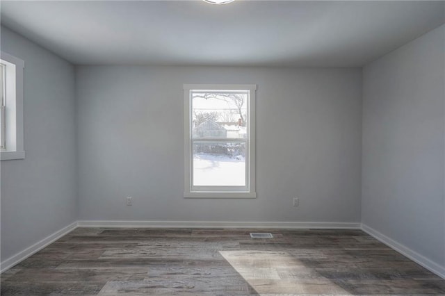 unfurnished room featuring visible vents, baseboards, and dark wood-style flooring