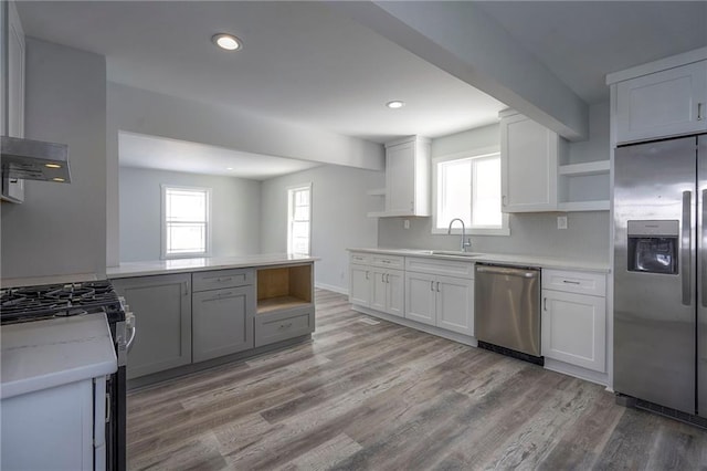 kitchen with light wood-style flooring, open shelves, a sink, stainless steel appliances, and light countertops
