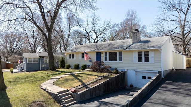 ranch-style house with a garage, driveway, a chimney, and a front lawn