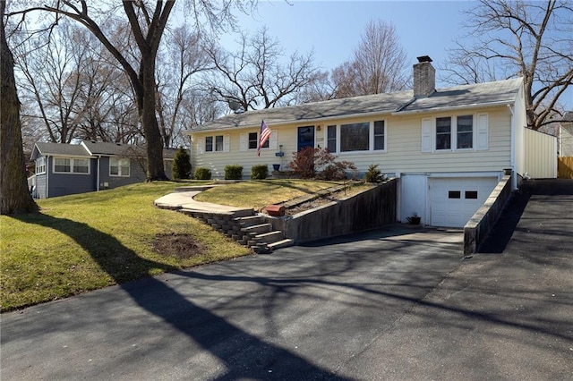 single story home with aphalt driveway, a front lawn, a garage, and a chimney