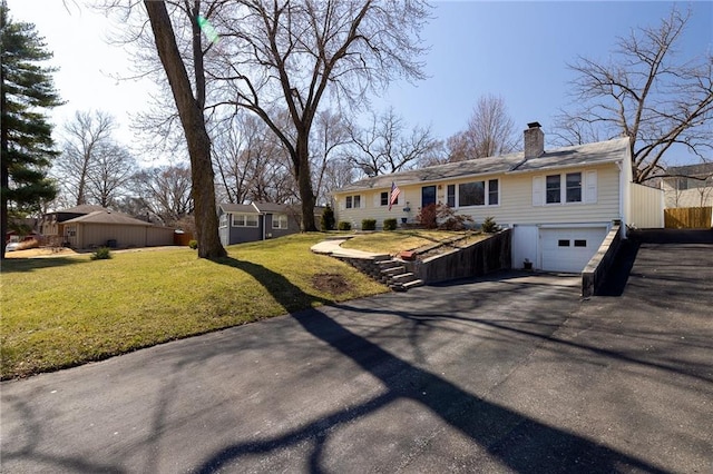 view of front of house with fence, driveway, a chimney, a front lawn, and a garage