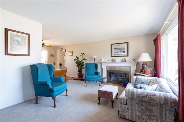 carpeted living room with a glass covered fireplace, a ceiling fan, and baseboards