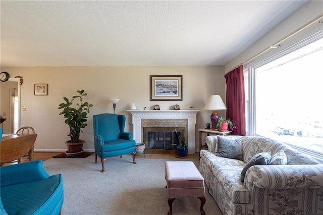 living room featuring baseboards, a fireplace with flush hearth, and carpet floors