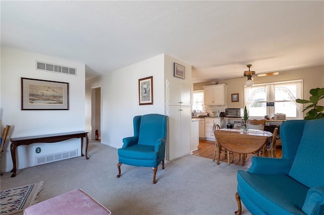 living room featuring a toaster, visible vents, light colored carpet, and ceiling fan