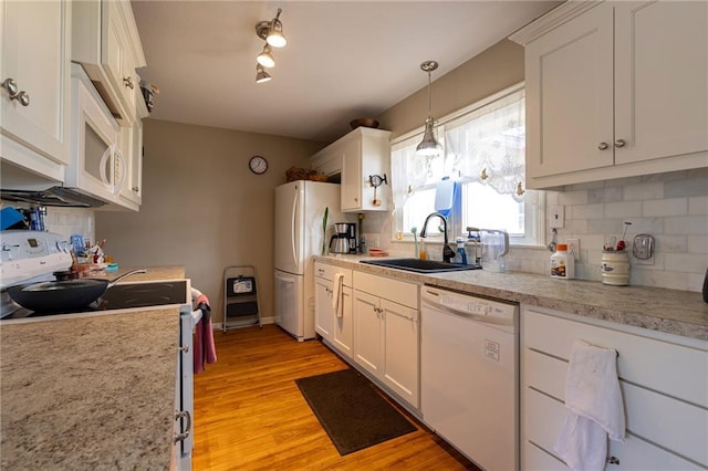 kitchen featuring white appliances, light wood-style flooring, a sink, white cabinets, and backsplash