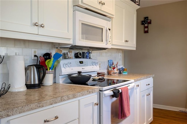 kitchen with white appliances, white cabinets, light countertops, and tasteful backsplash