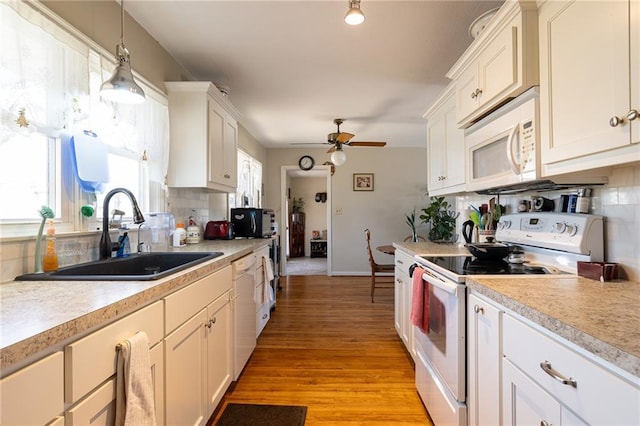 kitchen with tasteful backsplash, white appliances, light countertops, and a sink