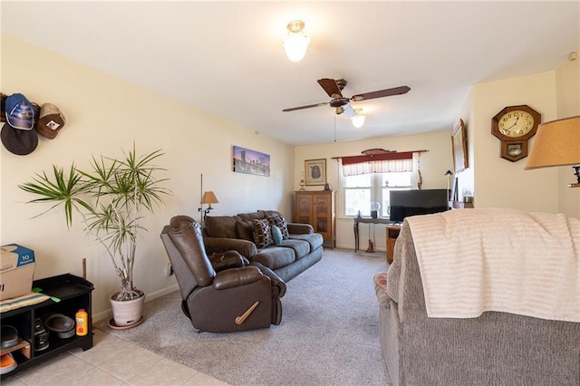 living area with carpet, a ceiling fan, baseboards, and tile patterned flooring