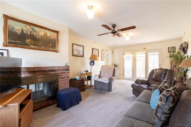 living room with carpet flooring, a brick fireplace, and a ceiling fan