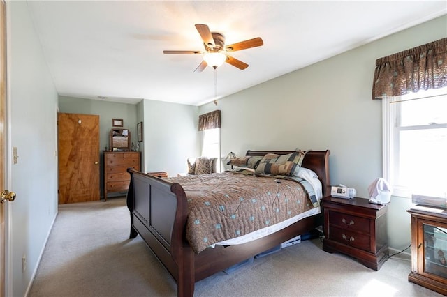 bedroom with multiple windows, light colored carpet, and a ceiling fan