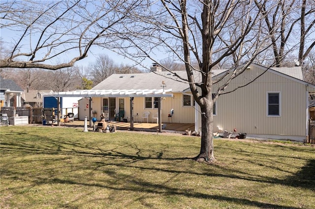 rear view of property featuring a yard, a chimney, and fence